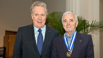 M. Charles Aznavour, arborant fièrement son insigne d