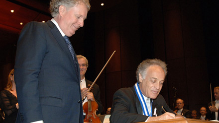 Moment solennel : M. Yoav Talmi appose sa signature dans le Livre d'or.